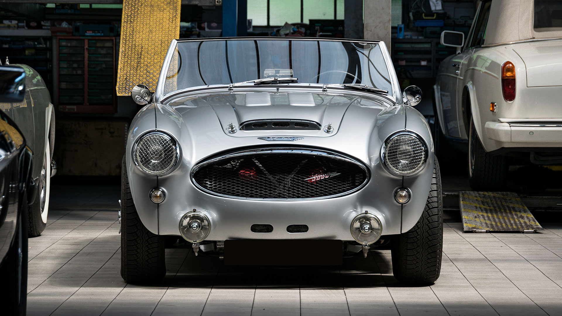 Clásico británico Austin Healey 3000 en garaje de coches clásicos. Hero imagen para una landingpage sobre recambios para su Austin Healey oldtimer. Enlaces a páginas web sobre recambios para Austin Healey británico.